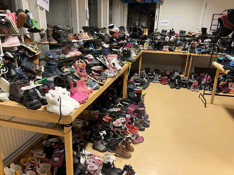 Massor av skor sorterade efter storlek står på golv och bord utmed väggarn.