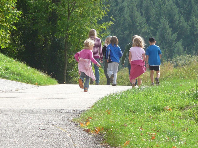 En barnfamilj går längs en väg